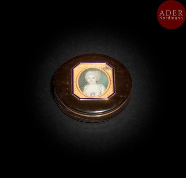 Portrait de femme à la robe ornée d’un nœud mauve au corsage, coiffure bouffante
Miniature sur ivoire, vers 1780, ovale à vue 3,7 x 3,1 cm.
Cadre à réverbère bordé d’un filet d’émail bleu, sur le couvercle d’une boîte ronde du début du XIXe siècle en composition de poudre d’écaille montée en or, l’intérieur garni d’or. 
Quatre poinçons sur la bâte de la base, idem sur la monture, deux poinçons usés sur la bâte du couvercle ; poinçon du M.O. : A.T. dans un losange, Antoine Torlet, insculpe en 1798
Diam. 8,6 cm, H. 2 cm, poids brut : 91 grammes (très petits accidents, la monture en or se détache de la base ; verre pleureur ; miniature non examinée hors du cadre)