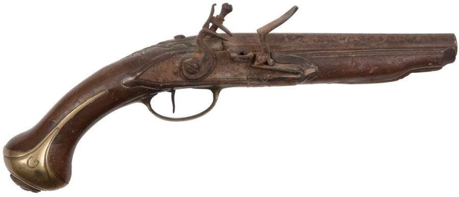 Pistolet d’arçon à silex 
Canon à pans (raccourci). Platine et chien à corps plat. Garnitures en laiton découpé et gravé. Calotte au masque grimaçant. 
Dans l’état. Vers 1750