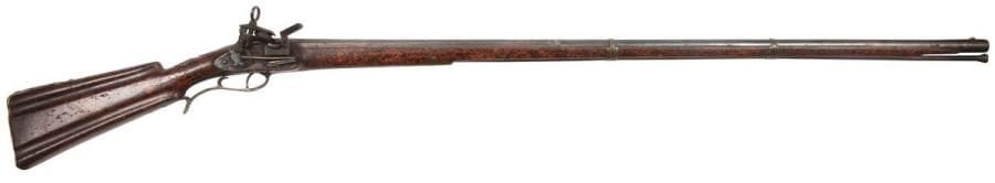 Fusil de chasse à silex
Canon rond tromblonné à la bouche, à pans au tonnerre, poinçonné « DGO » et d’un lion.
Platine à la miquelet. Garnitures en laiton découpé, gravé, rehaussé de médaillons en argent (usures). Pièce de pouce en argent. Crosse en trompe-l’œil façon ronce de noyer. Baguette en fanon.
Garniture et crosse ornées d’un profil de souveraine volontairement effacé. 
A.B.E. Espagne, vers 1760-1780.