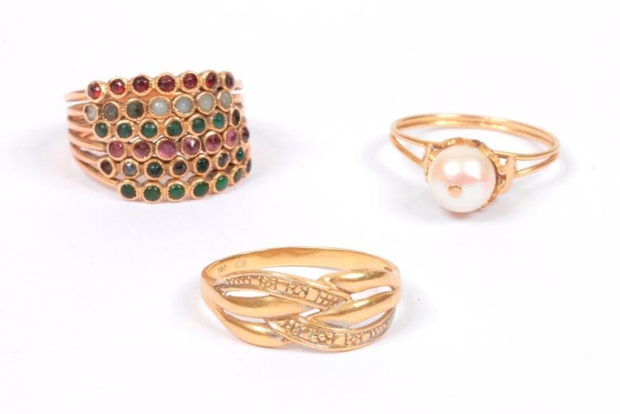 Lot de 3 bagues en or 18K (750 ‰), l'une sertie de pierres de couleurs, l'autre ornée d'une perle de culture, la dernière ciselée. 
Poids brut : 9 g (manques)