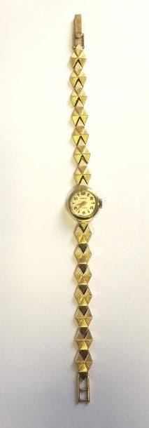Montre de dame en or 18K (750 ‰), cadran rond, bracelet en or 18K articulé de maillons losangiques imbriqués. Longueur : 17 cm environ. 
Poids brut : 14,6 g