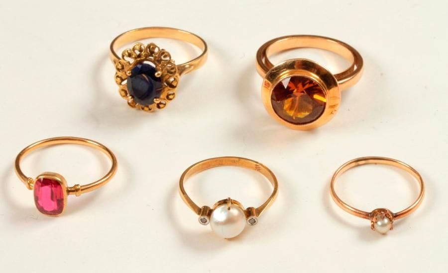 Lot de 5 bagues en or 18K (750 ‰), ornées de pierres fantaisie ou de perles de culture. Poids brut : 15,7 g