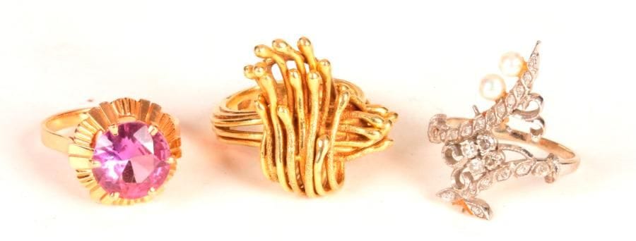 Lot de 3 bagues en or 18K (750 ‰), l'une sertie de diamants et de perles, l'autre ornée d'une pierre violette, la dernière formant un motif abstrait. 
Poids brut : 18,8 g (manques)