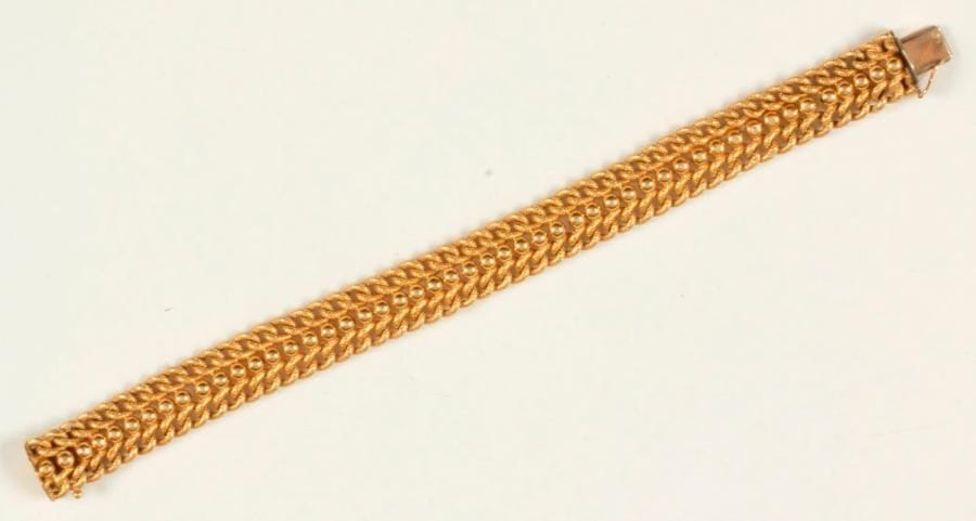 Bracelet en or 18K (750 ‰), articulé de maillons enchevêtrés enserrant une ligne de billes. Longueur : 19,3 cm environ. 
Poids : 21,9 g (enfoncements)