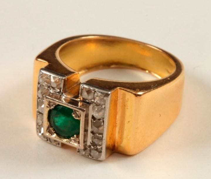 Chevalière en or 18K (750 ‰), ornée d'une émeraude ronde épaulée de diamants de taille ancienne. Travail des années 1940. Tour de doigt : 53. 
Poids brut : 9,4 g