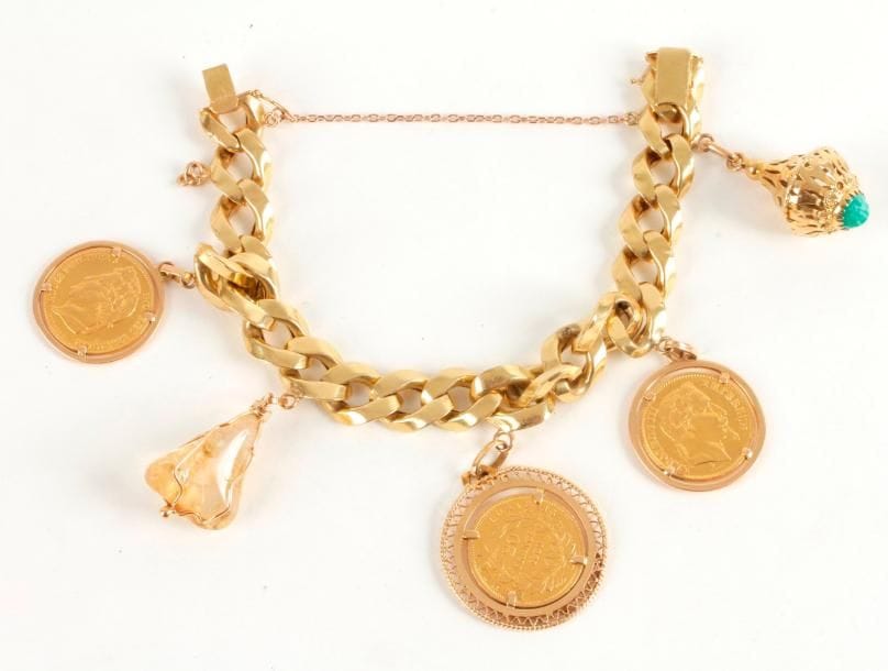 Bracelet maillons gourmette en or 18K (750 ‰), retenant en pampilles 3 pièces en or et deux breloques. Longueur : 21,5 cm environ. 
Poids brut : 64,5 g