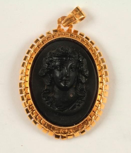 Pendentif en or 18K (750 ‰), orné d'un camée moulé en verre représentant une jeune femme de 3/4. Hauteur : 4,2 cm environ. 
Poids brut : 16,7 g