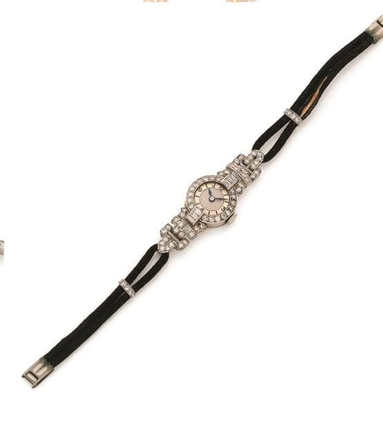 Montre de dame en platine, cadran rond serti de diamants, les attaches en platine formant des motifs géométriques imbriqués sertis de diamants ronds et calibrés, bracelet double queue de rat sur lequel coulissent deux barrettes serties de diamants. Travail français des années 1930. Longueur : 16 cm environ. Poids brut : 13,1 g