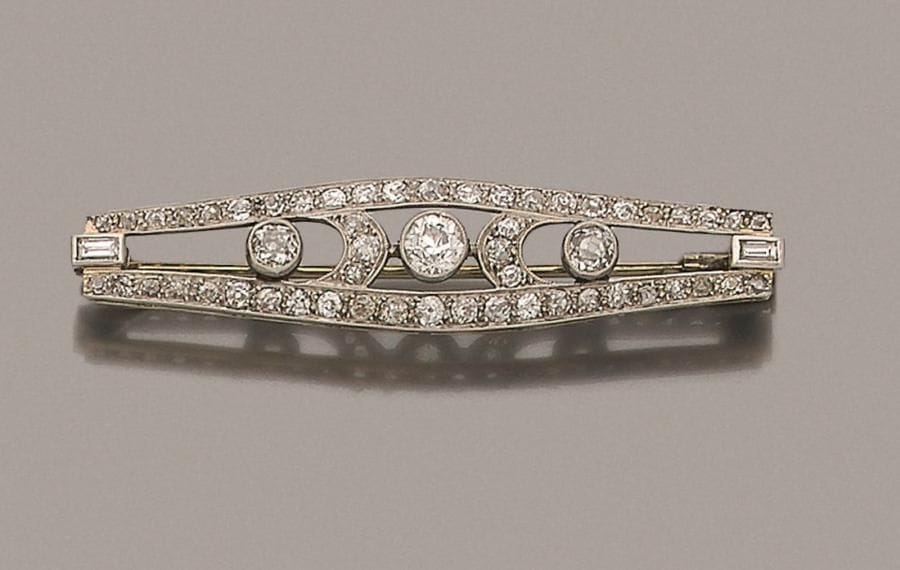 Broche fuseau en platine et or gris 18K (750 ‰), ajourée, sertie de diamants ronds de taille ancienne, les extrémités agrémentées chacune d’un diamant calibré. Travail des années 1920. Longueur : 5,4 cm environ. 
Poids brut : 7 g 