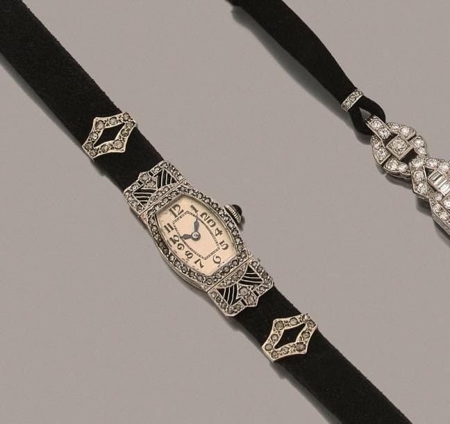 Montre de dame en or gris 18K (750 ‰), cadran oblong agrémenté de diamants taillés en roses, index chiffres arabes, les anses ajourées d’arcatures, le bracelet souligné de deux motifs losangiques agrémentés de diamants taillés en roses. Travail français des années 1920. 
Poids brut : 16 g