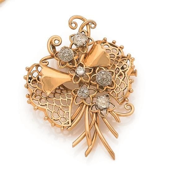 Broche-pendentif en or 18K (750 ‰), ajouré en bouquet stylisé, orné de deux diamants de taille ancienne et de diamants plus petits. Travail français des années 1940. Hauteur : 5,6 cm environ. 
Poids brut : 22 g (chocs)