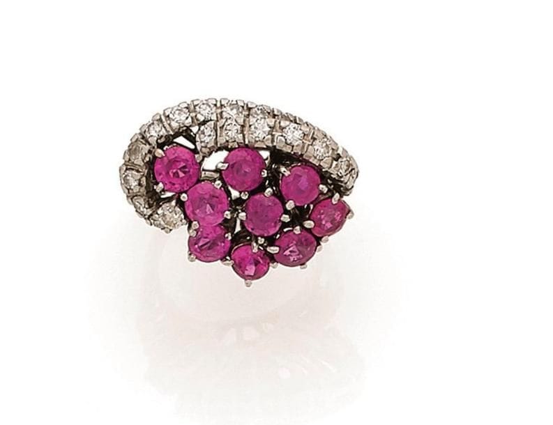 Bague en or gris 18K (750 ‰) asymétrique, formant un motif sinueux, ornée de diamants et de rubis naturels et synthétiques ronds. Tour de doigt : 49. 
Poids brut : 8,8 g (chocs)