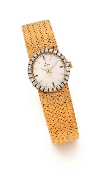 OMEGA. Montre de dame en or 18K (750 ‰), cadran rond serti de diamants, fond crème, index batons, bracelet ruban en or 18K tressé, guilloché, mouvement mécanique. Longueur : 16,5 cm environ. 
Poids brut : 40,4 g (mouvement à réviser, remontoir métal)