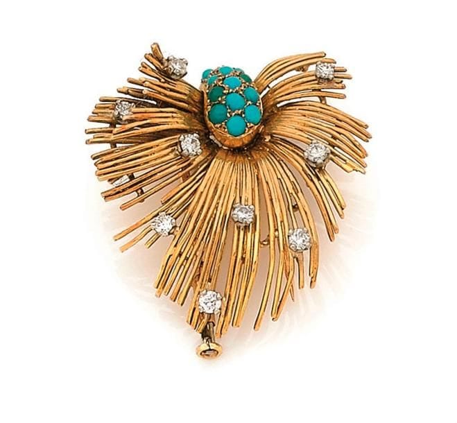 Broche-clip palme stylisée en fils d’or jaune 18K (750 ‰), pavée de turquoises et imitations cabochons, piquée de diamants ronds. Travail des années 1960. Hauteur : 3,4 cm environ. 
Poids brut : 11 g