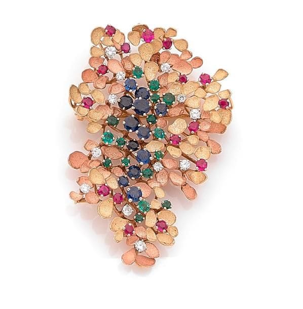 Broche bouquet stylisé en or 18K (750 ‰), sertie de diamants, de rubis, saphirs et émeraudes ronds, les feuilles amaties. Travail des années 1960. 
Hauteur : 5,7 cm environ.
Poids brut : 20,6 g