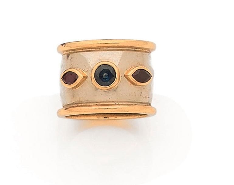 POIRAY. Bague large anneau en or gris et godron jaune 18K (750 ‰), sertie d’un saphir rond épaulé de rubis navettes sertis clos. Signée. Dans son écrin. Tour de doigt : 53. 
Poids brut : 13,9 g (égrisures)