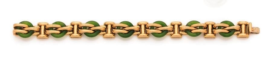 Bracelet en or 18K (750 ‰), articulé de 7 anneaux en jade appliqué d’attaches. Longueur : 19 cm environ. 
Poids brut : 73,3 g