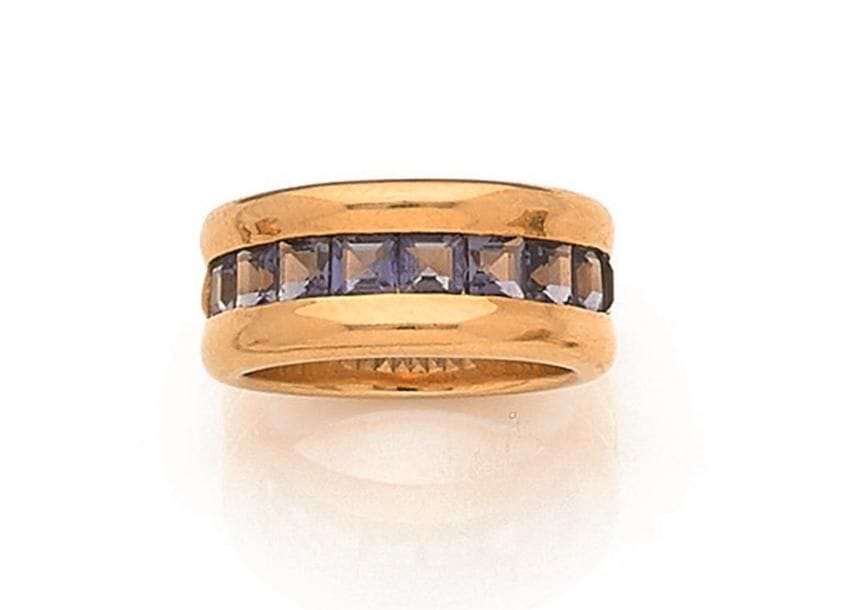 POIRAY. Bague jonc large en or 18K (750 ‰), sertie d’une ligne de 9 pierres bleues calibrées. Signée et numérotée. Tour de doigt : 54/55. 
Poids brut : 14,2 g