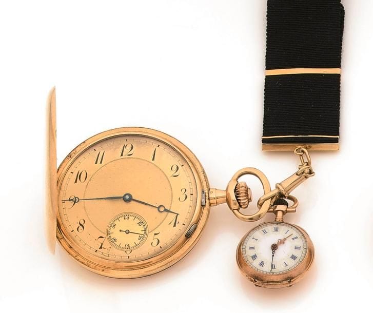 Lot de 2 montres de poches en or 18K (750‰). Une montre de type savonnette, cadran peint chiffres arabes formant les heures, trotteuse à 6H, mouvement à remontoir ; une montre de col, cadran émaillé blanc, mouvement à remontoir boîtier décoré d’initiales.
On y joint une châtelaine en tissu et or.
Poids brut de l’ensemble : 88,8 g