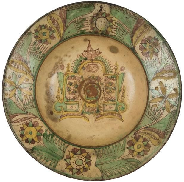 Tarn, Giroussens, XVIIIe siècle
Grand plat en terre rouge à l’engobe jaune, vert et brun sur fond blanc sous vernis plombifère, à décor central du retable de la chapelle dédiée à Sainte Rufine patronne des potiers et sur le marli, en empreinte sigillée, les armes de France. 
Restauration aux agrafes.
Diamètre : 40,4 cm