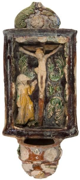 ?Allemagne du Sud, Marbourg, XVIIIe - XIXe siècle
Bénitier en terre vernissée en forme de niche flanquée d’un fronton et d’une vasque, décoré en pastillage sur fond brun du Christ en croix et à ses pieds un saint personnage (probablement Saint François d’Assise) sur un fond de feuilles d’acanthe en rappel sur le fronton et la vasque. Accidents et manques.
Hauteur : 33,8 cm - largeur : 14,5 cm - hauteur : 7 cm