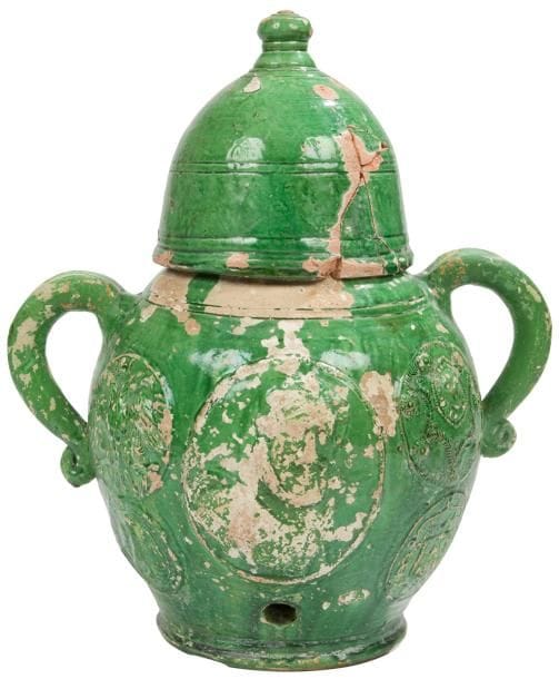 ?Saintonge, XVIIe siècle
Fontaine de table en terre vernissée émail vert et son couvercle en forme de cloche. Le corps ovoïde est doté de deux anses plates terminées en enroulement, au centre du corps figure dans un médaillon central en applique le portrait d’Henri IV, à droite des armoiries d’une famille française et à gauche deux aigles héraldiques.
Nombreuses restaurations au couvercle et aux anses, sautes d’émail et manques.
Hauteur : 42 cm - diamètre : 25 cm
