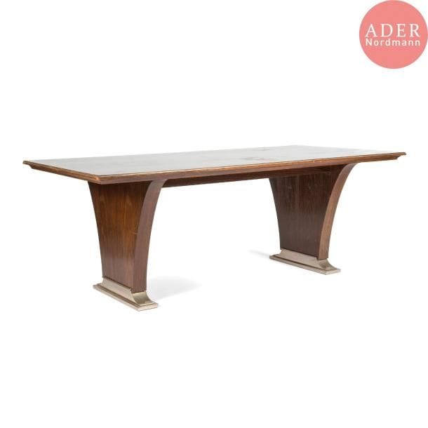 Léon JALLOT (1867-1974) & Maurice JALLOT (1900-1971)
Grande et élégante table de salle à manger en placage de chêne européen teinté. Le plateau, au fin bandeau mouluré, reçoit un jonc en métal nickelé sur tout son pourtour. Les pieds, en plot de forme tulipe, reposent sur une base en doucine achevée par des enroulements et accueillie par un large patin, l'ensemble de la réception réalisé en métal nickelé. Circa 1932 / 35. 73 x 198 x 100 cm 

Bibliographie : 
Nouveaux intérieurs français, 3ème série - Éditions Charles Moreau, Paris. Modèle identique reproduit planche 12. 
Art & Décoration - Année 1934. Modèle identique reproduit page 183.
Ensembles mobiliers, volume V - Éditions Charles Moreau, Paris. Modèle identique reproduit planche 6.


