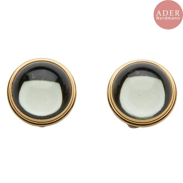 Maison LALIQUE d'après un modèle de Marie-Claude LALIQUE (1935-2003) 
Cabochon
Paire de clips oreille en cristal gris-bleu et métal doré. Chaque cabochon signé LALIQUE France au revers de la platine. D. 2,5 cm
