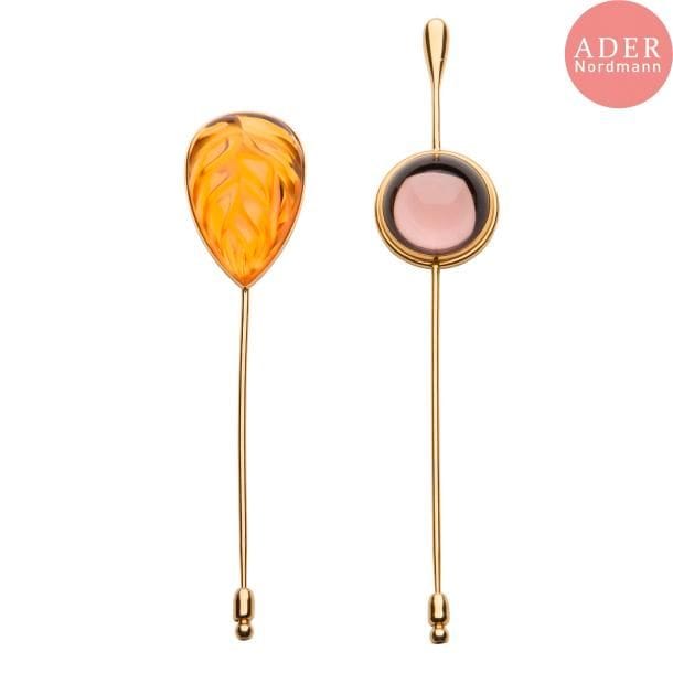 Maison LALIQUE d'après un modèle de Marie-Claude LALIQUE (1935-2003) 
Cabochon et Héliconia
Réunion de 2 épingles à chapeau, en cristal parme pour l'une, orange pour l'autre, et métal doré. Chacune signée LALIQUE France au revers de la platine. L. 11 & 13 cm
