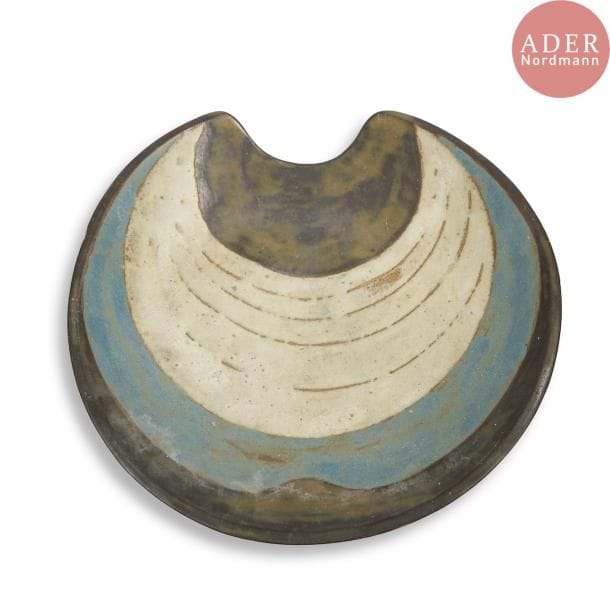 François BOQUEL (1928-2017)
Grand plat circulaire creux, à une encoche. Épreuve en céramique à décor émaillé polychrome de croissants concentriques. Un éclat sur le pourtour. Monogrammé F.B. et sous la base. D. 41 cm
Né à Nancy le 15 août 1928, François Boquel quitte l’école et sa famille à 16 ans. 

Né à Nancy le 15 août 1928, François Boquel quitte l’école et sa famille à 16 ans. Fasciné par les arts du feu, c’est en parfait autodidacte qu’il s’installe à Vallauris dans les années 1950. Dans le village, il travaillera notamment à l’Atelier Les Archanges aux côtés de Gilbert Valentin. Il nouera également à cette époque une solide amitié avec le peintre André Cottavoz, avec qui il restera longtemps en contact, le céramiste François Raty, mais aussi Jacques Prévert avec lequel il aimait échanger sur l’art.  Il s’installe en Île-de-France dans les années 1960, région qu’il ne quittera plus jusqu’à son décès à Meudon en 2017. Bien qu’éloigné géographiquement du village aux cent potiers, il ne cessera de pratiquer l’art de la céramique, en témoignent les œuvres présentées ci-après.