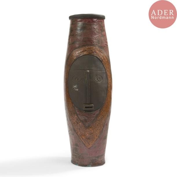François BOQUEL (1928-2017)
Visage africaniste, 1995
Grand vase fuselé à col ourlé. Épreuve en céramique émaillée lie-de-vin, à décor sur une face d'un visage stylisé traité noir mat, sur l'autre d'une composition abstraite émaillée polychrome. Éclats et cheveux à la base. Monogrammé F.B., daté 4-(19)95 et porte l'inscription CHF sous la base. H. 65 cm
Né à Nancy le 15 août 1928, François Boquel quitte l’école et sa famille à 16 ans. 

Né à Nancy le 15 août 1928, François Boquel quitte l’école et sa famille à 16 ans. Fasciné par les arts du feu, c’est en parfait autodidacte qu’il s’installe à Vallauris dans les années 1950. Dans le village, il travaillera notamment à l’Atelier Les Archanges aux côtés de Gilbert Valentin. Il nouera également à cette époque une solide amitié avec le peintre André Cottavoz, avec qui il restera longtemps en contact, le céramiste François Raty, mais aussi Jacques Prévert avec lequel il aimait échanger sur l’art.  Il s’installe en Île-de-France dans les années 1960, région qu’il ne quittera plus jusqu’à son décès à Meudon en 2017. Bien qu’éloigné géographiquement du village aux cent potiers, il ne cessera de pratiquer l’art de la céramique, en témoignent les œuvres présentées ci-après.