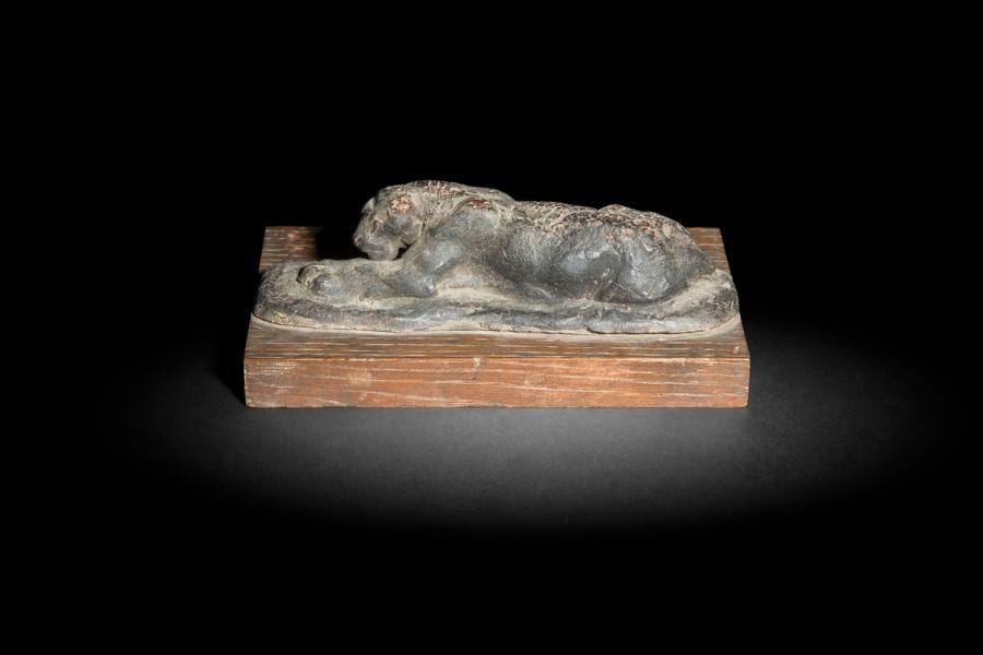 Antoine-Louis Barye (1796-1875) attribué à
Jaguar au repos
Esquisse en cire
H : 4 x L : 15 x l : 5 cm ; repose sur une base en bois ; H : 1 x L : 15 x l : 9,7 cm
Porte une étiquette annotée « cire Barye et le n°226 »

Œuvres en rapport : 
Jaguar dévorant un agouti et Jaguar couché tenant une tête de cheval ; Michel Poletti et Alain Richarme, Barye, catalogue raisonné des sculptures, Paris, 2000, p.234 et p.237, modèles référencés sous les n°sA94 et A97

Cette esquisse pourrait être une étude préparatoire pour des modèles créés par Barye à la fin des années 1830 et au début des années 1840. Le Jaguar dévorant un agouti et le Jaguar couché tenant une tête de cheval correspondent en effet dans les grandes lignes de composition à cette esquisse. D’autres exemples de travaux préparatoires de Barye participant du même processus de création passant par une étude en cire du modèle vivant sont conservés au musée du Louvre (Cheval cabré, RF 1589 ; Tigre couché en sphinx, RF236 ou encore Tigre couché, RF237).