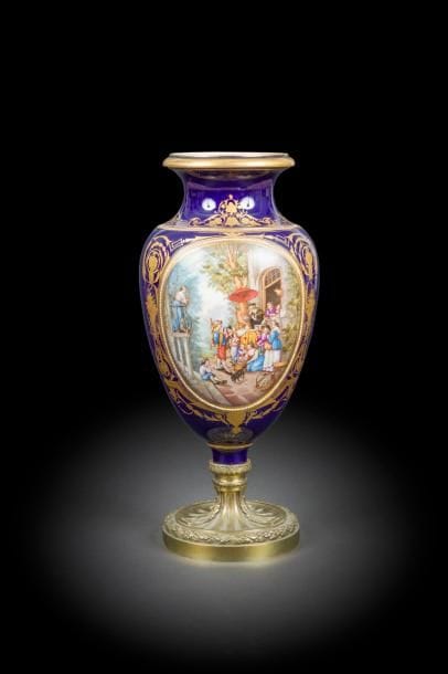 Dans le goût de Sèvres.
Vase balustre en porcelaine à fond bleu et or à décor polychrome dans une réserve d’une scène de marchandage. 
Monture en bronze doré de style Louis XVI
H : 46 cm