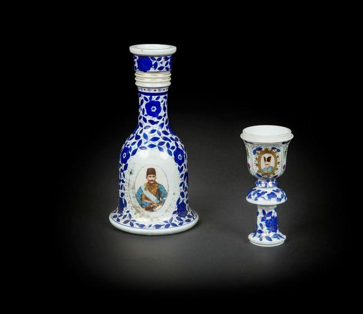 Base de narghilé en porcelaine aux portraits de Nasir al-Din Shah et Mozafar -ed- din shah Qajar, Europe pour le marché iranien, fin XIXe siècle
Base campaniforme à décor de médaillons des shahs sur fond floral bleu. Avec son fourneau reprenant les médaillons des portraits des shahs.
H. : 26 cm et fourneau : 16 cm
État : fourneau, fracture recollée.

A porcelain qalyan base with portraits of Nasir al-Din Shah and Muzaffar al-Din Shah Qajar, Europe for the Iranian market, late 19th century
