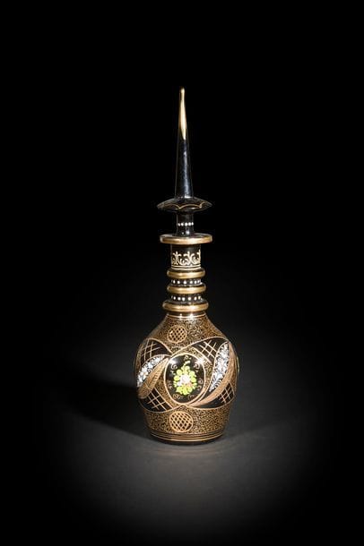 Carafe aux médaillons fleuris, Iran Qajar, fin XVIIIe - déb. XXe siècle
En verre bleu foncé à panse ovoïde, col annelé et bouchon en pointe, à décor incisé et peint en or et polychromie de médaillons fleuris ceinturés de palmes.
H. : 60 cm

A Qâjâr glass bottle and tapering stopper, Iran, 20th century