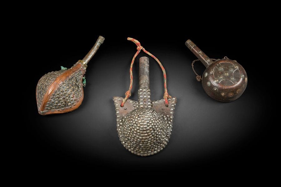 Trois poires à poudre en bois, cuir et cloutées, Foum Zguid, Présahara et Maroc, Moyen Atlas
La première à panse ronde sculptée d’un motif cruciforme clouté, la seconde à panse recouverte de cuir et de clous et la dernière à ailettes en cuir et entièrement cloutée.
L : 30,5, 23 et 29, 5 cm
Pour d’autres exemples, voir le catalogue de l’exposition Splendeur du Maroc, Tervuren, 1998, pp. 22-23.

Three wood and studded leather powder horns, Africa