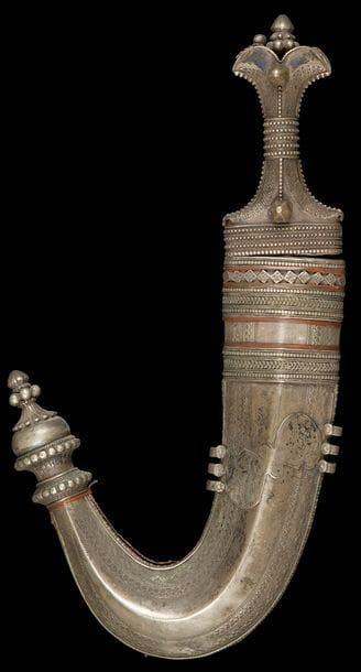 Poignard, jambiya, Yémen, fin XIXe siècle
Lame courbe à double tranchant et nervure médiane. Monture en argent à décor gravé délimité par des frises perlées et ponctuée de deux cabochons en argent. Fourreau en argent à décor gravé de frises géométriques et d’une inscription en alphabet sud arabique. Bouterolle en dard et frises d‘argent perlées et tressées alternant avec des liens de cuir sur la partie supérieure. Revers recouvert de cuir.
L. : 37 cm ; PB : 787 g
État : oxydation de la lame, usures du cuir du fourreau.

A Yemeni horn-hilted dagger, jambiya, 19th century 