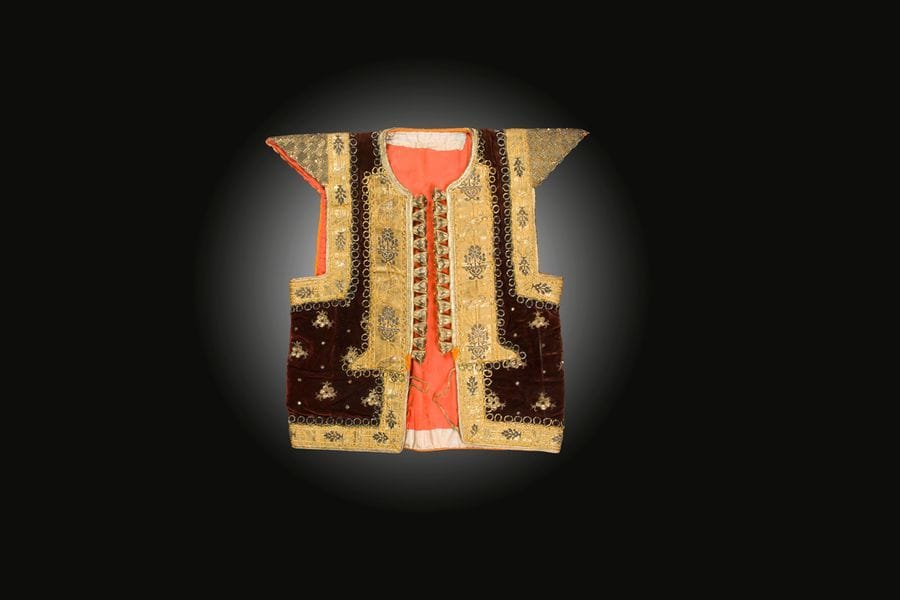 Gilet de mariage, farmla, Tunisie, Nabeul, XXe siècle
Gilet ouvert sans manches, à épaulettes rigides et col rond, en velours brun brodé de fleurs et poissons en fils métalliques et pastilles dorées. Galon métallisé rehaussé de vases fleuris sur le pourtour.
H. : 55 cm et largeur avec manches : 55 cm
Bibliographie : Vivier M.F., Noces tissées et Noces brodées, Exposition Musée des Arts d’Afrique et d’Océanie, 29 mars au 3 juillet 1995, Paris, p. 96.

A wedding jacket, farmla, Tunisia, Nabeul, 20th century