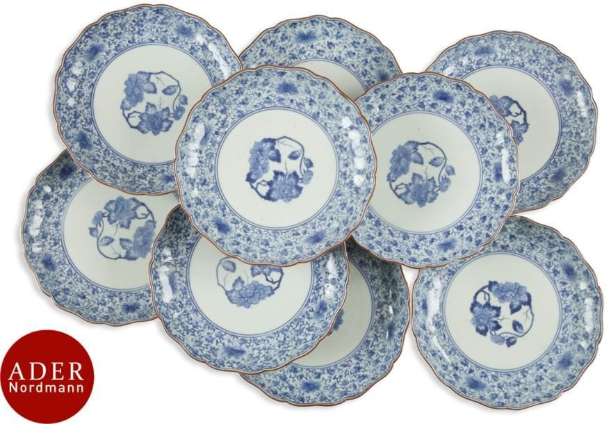 JAPON - Époque MEIJI (1868 - 1912)
Neuf coupes en porcelaine polylobées bleu blanc à décor central de branche fleurie, de frises de lotus dans leur feuillage en réserve. Marque Fuku. 
Diam. : 21,5 cm (fêlures, éclats).