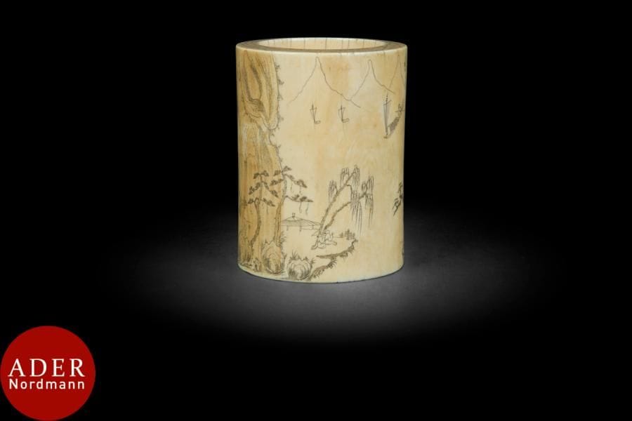 CHINE - XVIIIe siècle
Pot à pinceaux bitong en ivoire, le fond en bois, à décor incisé d’un paysage montagneux jonché de pins et de saules pleureurs, des bateaux à voile voguant sur le lac, et d’un poème.
H : 11, 6 cm. Diam. : 8, 8 cm