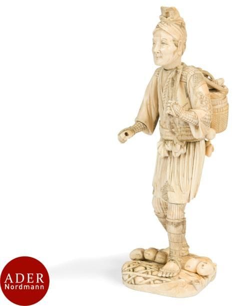 JAPON - Époque MEIJI (1868 - 1912)
Important okimono en ivoire, pêcheur debout marchant, tenant son panier rempli de poissons sur le dos à l’aide d’une corde. 
H : 35 cm (manque un élément dans sa main droite, éclat sur le socle, gerces, restauration).