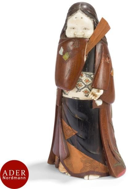 JAPON - Époque MEIJI (1868 - 1912)
Statuette en bois et ivoire d’Okame debout, tenant l’éventail devant sa bouche, la robe à décor incrusté en nacre et pierre dure de chidori en vol. 
H : 20 cm (manques et restauration).