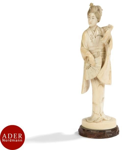 JAPON - Époque MEIJI (1868 - 1912)
Okimono en ivoire, jeune femme en kimono debout tenant un éventail de la main droite, un tissu de la main gauche. 
H : 19,2 cm ; sur socle en bois.