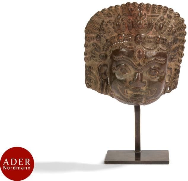 NEPAL - XVIIIe siècle
Masque de Bhairava en cuivre repoussé, les yeux grands ouverts, la tête ornée d’une couronne parsemée de crâne de citipati. 
H : 10,2 cm ; sur socle en bronze.