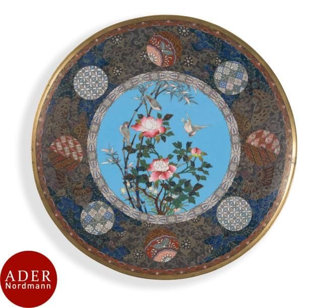 JAPON - Époque MEIJI (1868 - 1912)
Paire de plats en cuivre et émaux cloisonnés à décor d’oiseaux parmi les pivoines sur fond turquoise, l’aile ornée de médaillons de motifs géométriques et de papillons.
Diam. : 37 cm