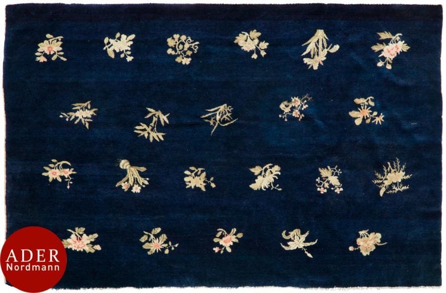 CHINE 
Tapis en laine (trame coton) à décor sur fond bleu nuit de semis de fleurettes roses. 
Dim. : 185 x 130 cm