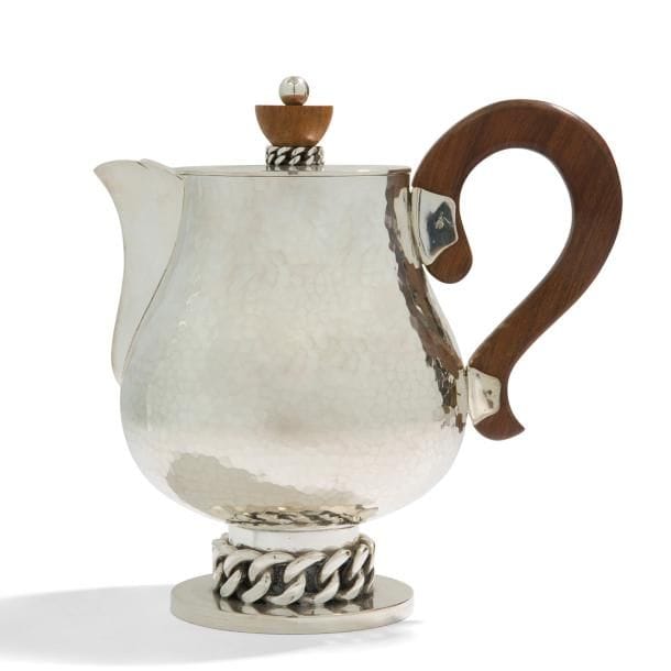JEAN DESPRÉS (1889-1980)

Élégant serveur à café ou à thé, en métal argenté, à une anse détachée en palissandre.
Épreuve en métal argenté.
Le corps du verseur, achevé en martelage, repose sur un pied orné d’une épaisse gourmette à maillons plats et reçu par une base circulaire traitée lisse.
Le couvercle, également traité lisse, reçoit la graine en palissandre reposant sur une petite gourmette tournante.
Signé et daté J. DESPRÉS 16.(0)9.(19)67, à la pointe sous la base.
Hauteur : 20 cm

Provenance :
Ancienne Collection M. et Mme L. à Saint-Léger-Vauban, anciens commerçants avallonais. Œuvre acquise par ces derniers directement auprès de l’artiste.
