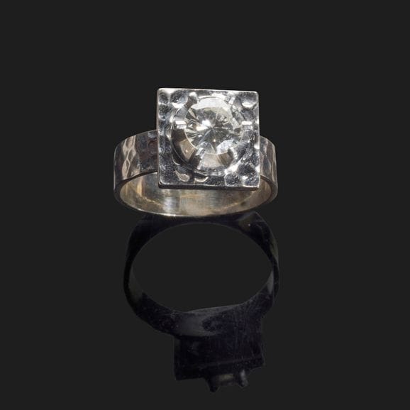 JEAN DESPRÉS (1889-1980)

Rare solitaire moderniste en platine.
La plateforme carrée à surface martelée accueille un diamant rond taille moderne de 0,9 ct (jolie couleur supposée, petit choc sur la table).
L’anneau présente également une surface martelée.
Signé Jean DESPRÉS à la pointe dans l’anneau et porte le poinçon de garantie sur l’anneau.
Poids brut : 6,45 g

Provenance :
Collection Mme T., Villiers-sur-Tholon.
