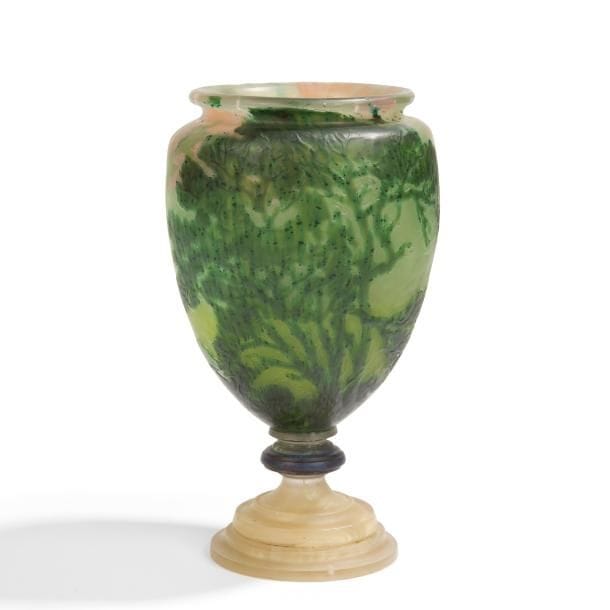 ÉMILE GALLÉ (1846-1904)

Arbre en frondaison, 1904
Rare vase en forme d’urne, à col étranglé et annulaire, reposant sur piédouche.
Épreuve en verre multicouche au décor dégagé à l’acide, traité vert foncé aux salissures intercalaires sur fond martelé vert tendre et vert moyen et entièrement repris en gravure à la roue.
Le pourtour du col reçoit une coloration rose en intercalaire.
Le piédouche à gradins, en verre à l’imitation de la pierre dure, collé à chaud sur la base du vase.
Un choc (d’origine ?) vers la base du corps ayant provoqué des cheveux en étoile et repris à la roue.
Signé et daté GALLÉ 1904 gravé en réserve sur un fond également gravé figurant des feuillages.
Hauteur : 19 cm

Provenance :
Collection particulière, Paris.

Bibliographie :
Le Verre - Art & Design XXe - XXIe siècles, volume 2 – Yves Delaborde, ACR éditions, Paris, 2011. Œuvre à rapprocher, d’une technique moins sophistiquée, reproduite page 133.