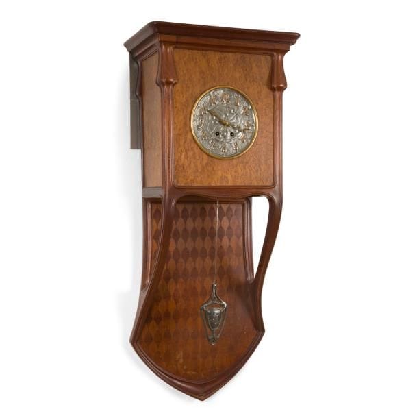 LOUIS MAJORELLE (1859-1926)

Horloge murale en acajou mouluré et sculpté et en placage de loupe d’Amboine.
La partie basse en écusson soutient la partie haute, plaquée toutes faces, grâce à deux supports curvilignes se poursuivant en montants terminés chacun par un renflement.
Le tablier présente un décor géométrique réalisé en marqueterie de bois précieux.
Le cadran en métal repoussé à patine argentée et dorée ; le balancier en bronze, également argenté.
Aiguilles en métal à l’évocation des pavots.
Époque Art nouveau.
Trous de ver sur la partie marqueterie.
113 x 45 x 28 cm

Œuvres en rapport et bibliographie :
Majorelle – Alastair Duncan, éditions Flammarion, Paris, 1991. Une horloge équipée du même cadran reproduite page 11.
